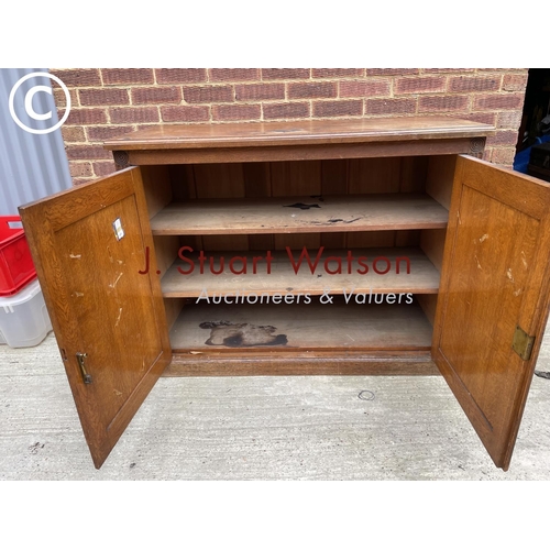 122 - An Edwardian oak two door school cupboard with two internal shelves