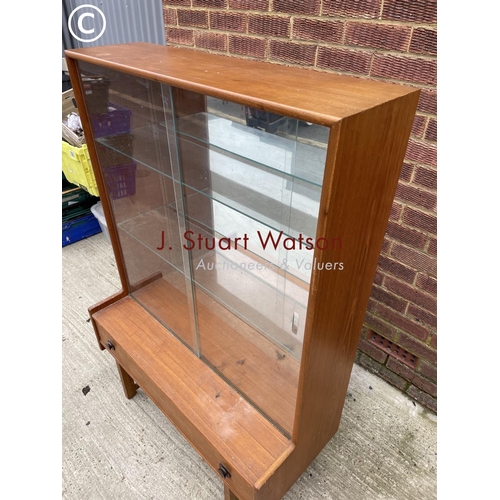 142 - A teak glazed display cabinet with a mirror glass interior over a single drawer