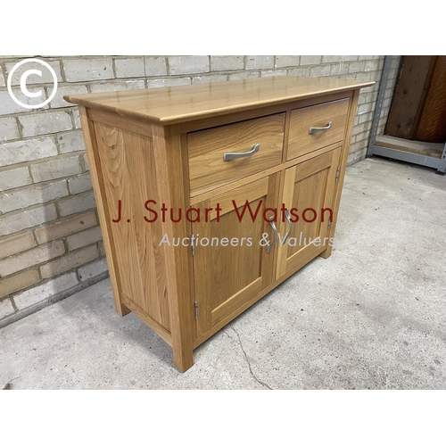 157 - A small light oak sideboard having two drawers over two cupboard doors