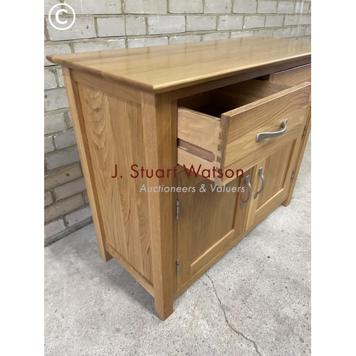 157 - A small light oak sideboard having two drawers over two cupboard doors