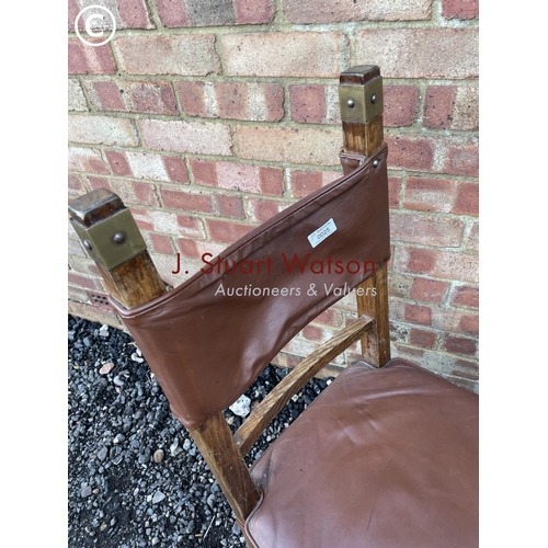 25 - An unusual oak chair with brown leather seat amd brass strapwork