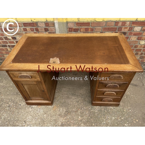 302 - An early 20th century oak pedestal desk with a brown leather top