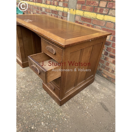 302 - An early 20th century oak pedestal desk with a brown leather top