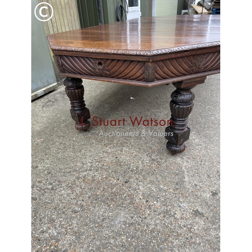 309 - A very large carved oak wind out dining table with three leaves, raised on 5 removable legs. With  H... 