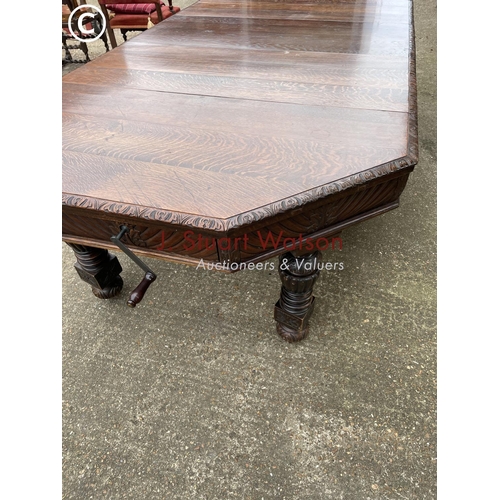 309 - A very large carved oak wind out dining table with three leaves, raised on 5 removable legs. With  H... 