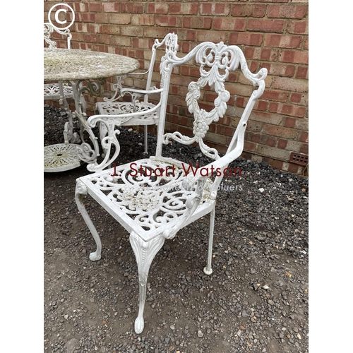 339 - An ornate circular aluminum white painted garden table together with four carver chairs 110 cm diame... 