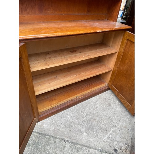 380 - An oak school room two door cupboard with bookrack top