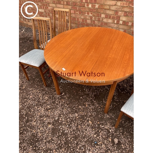 127 - An Alfred Cox extending circular teak table together with four chairs See image of labels