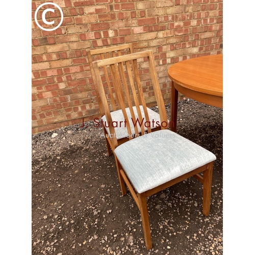 127 - An Alfred Cox extending circular teak table together with four chairs See image of labels