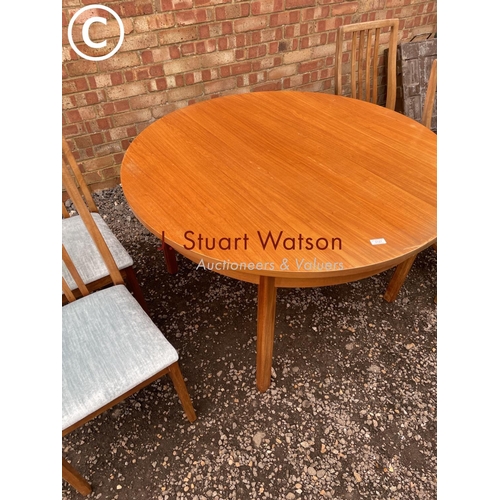 127 - An Alfred Cox extending circular teak table together with four chairs See image of labels