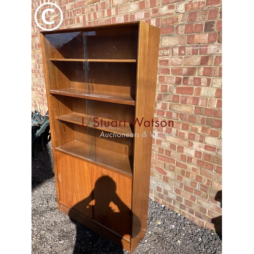 250 - A mid century glazwd bookcase cupboard with three adjustable shelves