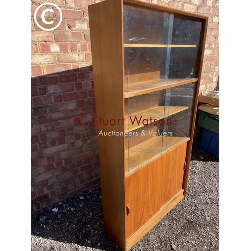 250 - A mid century glazwd bookcase cupboard with three adjustable shelves