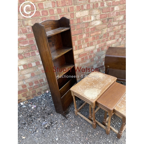 281 - A slim oak bookcase together with an oak nest of three and an oak tea trolley