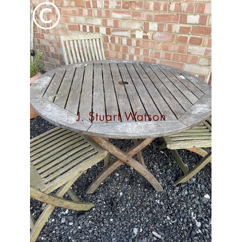 349 - A hardwood circular garden table together with three folding chairs 110cm diameter