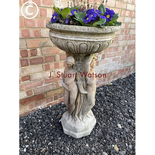 358 - An ornate cast concrete sculptural urn decorated with three ladies and planted with primrose 85 high