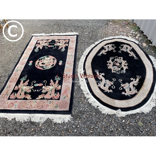 68 - A black rug and a black oval Chinese rug