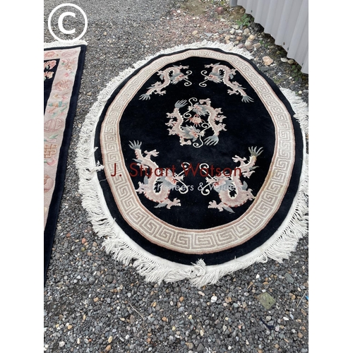 68 - A black rug and a black oval Chinese rug