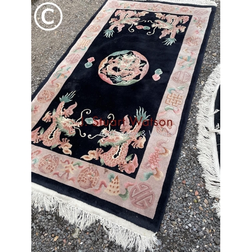 68 - A black rug and a black oval Chinese rug