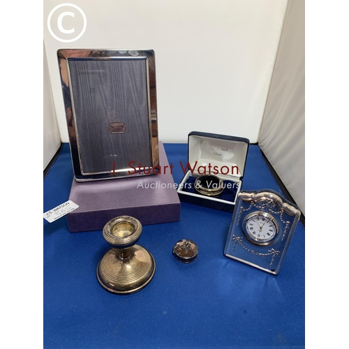 865 - Hallmarked Silver: Boxed photo frame 17 x 12 cms, small clock by R. Carr, candle stick, pill box and... 