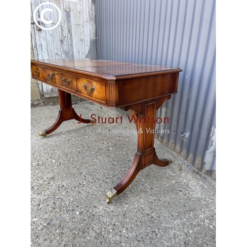 23 - A reproduction mahogany three drawer writing table with leather top