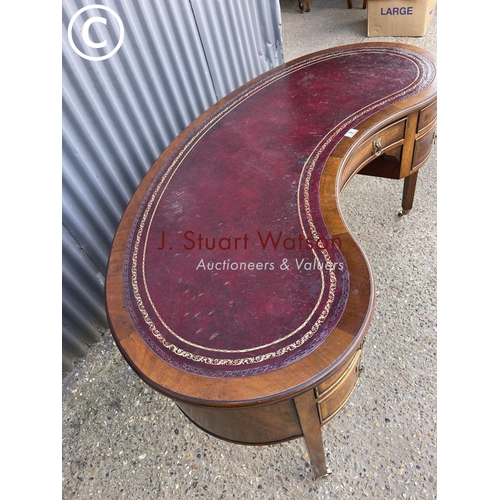 9 - A reproduction mahogany kidney shaped writing table with red leather top 148cm wide