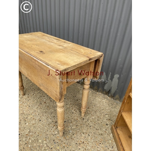 266 - A pine drop leaf kitchen table together with a small pine bookcase