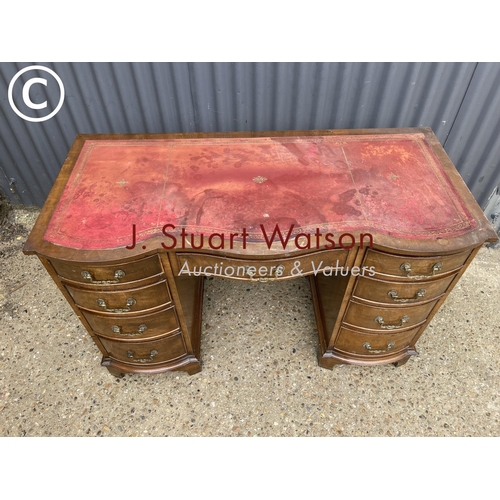 276 - A reproduction mahogany kneehole desk with a red leather top