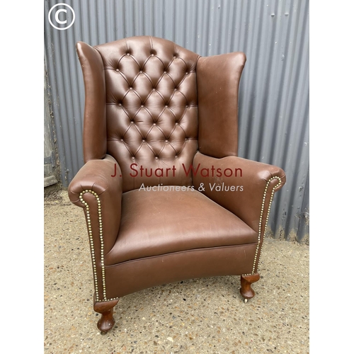 297 - A brown leather chesterfield wing back armchair