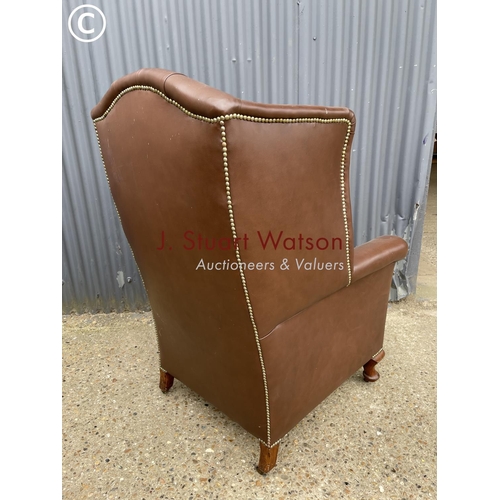 297 - A brown leather chesterfield wing back armchair