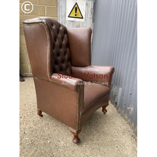 297 - A brown leather chesterfield wing back armchair