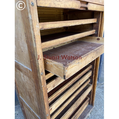 36 - An original vintage bakers 'bun cabinet' tambour front enclosing pine bun drawers. On large castors ... 