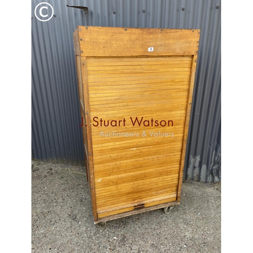 36 - An original vintage bakers 'bun cabinet' tambour front enclosing pine bun drawers. On large castors ... 