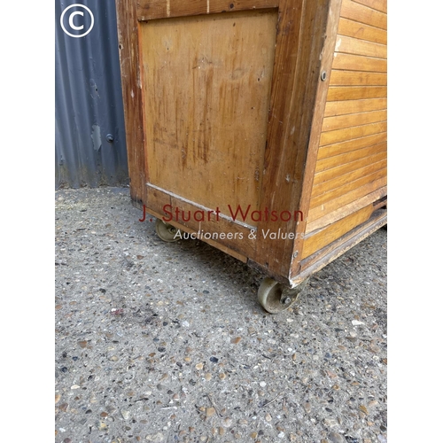 36 - An original vintage bakers 'bun cabinet' tambour front enclosing pine bun drawers. On large castors ... 