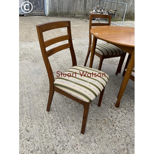 94 - A circular teak table together with four nathan dining chairs