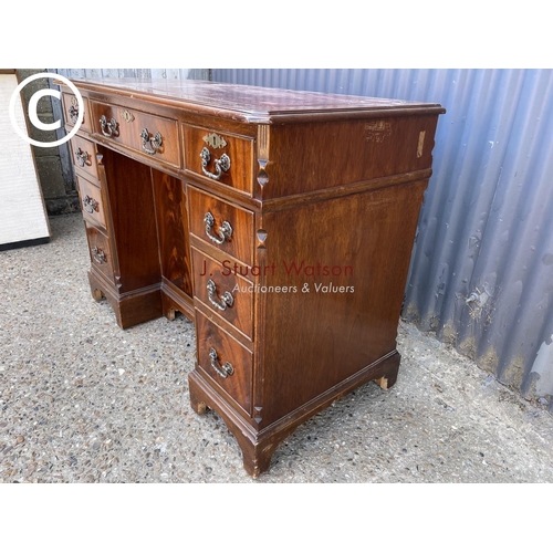 245 - A reproduction mahogany kneehole writing desk with a red leather top