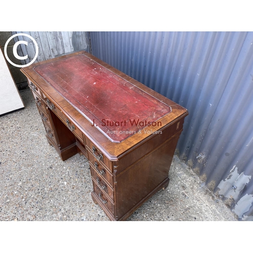 245 - A reproduction mahogany kneehole writing desk with a red leather top