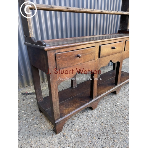 289 - An antique oak three drawer dresser base with later farmhouse style pine plate rack top 154cm wide