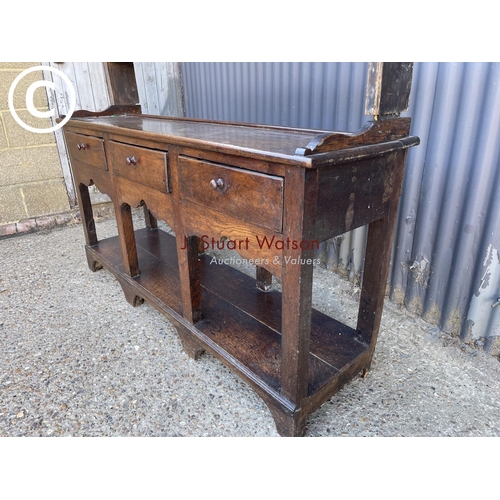 289 - An antique oak three drawer dresser base with later farmhouse style pine plate rack top 154cm wide