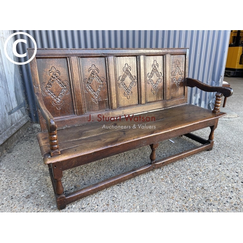 296 - An early oak settle bench seat with carved panel back 156cm wide