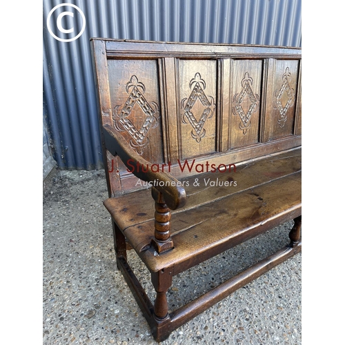 296 - An early oak settle bench seat with carved panel back 156cm wide