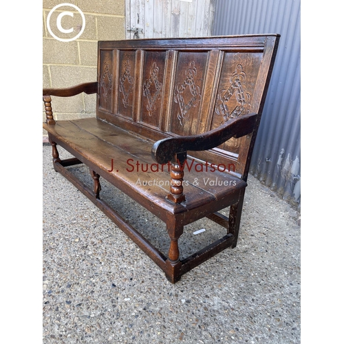 296 - An early oak settle bench seat with carved panel back 156cm wide