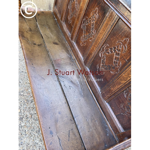 296 - An early oak settle bench seat with carved panel back 156cm wide