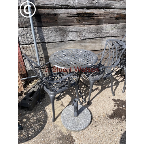473 - A small circular aluminium garden table and two chairs together with granite parasol stand