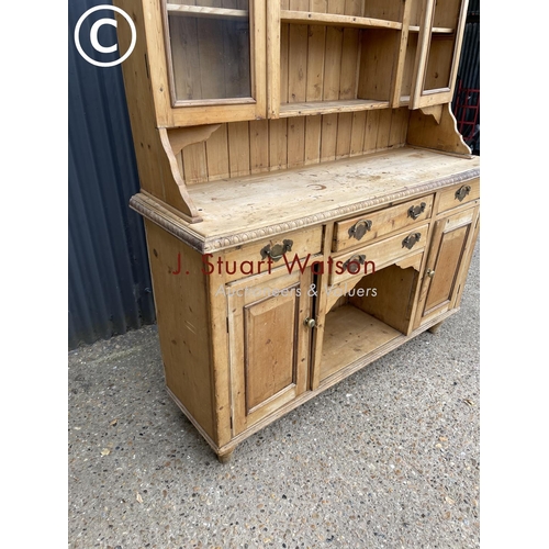 11 - A large antique pine dresser of South Wales Origin with glazed top(lacking one window) over four dra... 