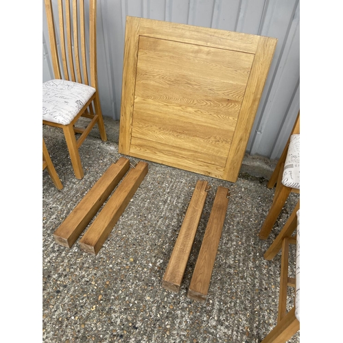 210 - A modern light oak drawer leaf table together with four chairs