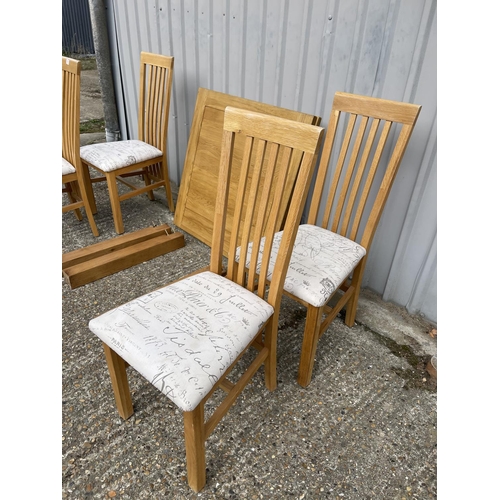 210 - A modern light oak drawer leaf table together with four chairs