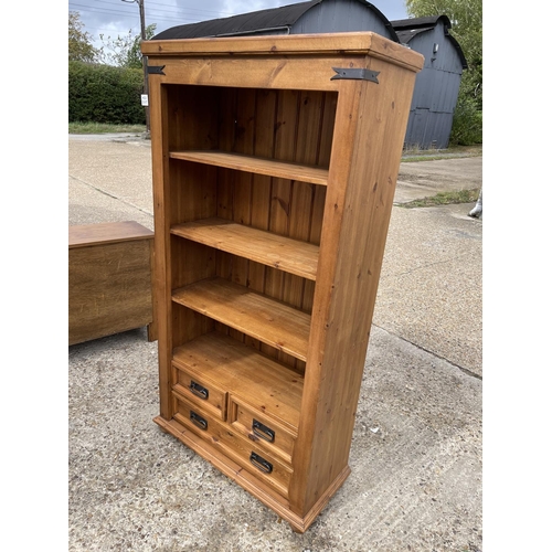 213 - A solid pine open fronted bookcase with three drawers