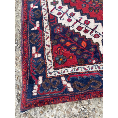 25 - A large red white and blue pattern rug 230x130