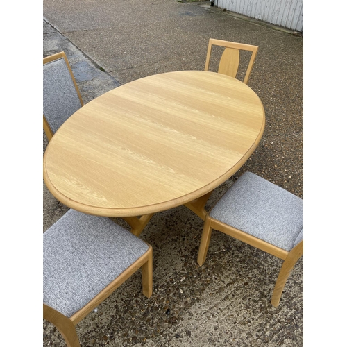 254 - A modern light oak oval dining  table together with four chairs