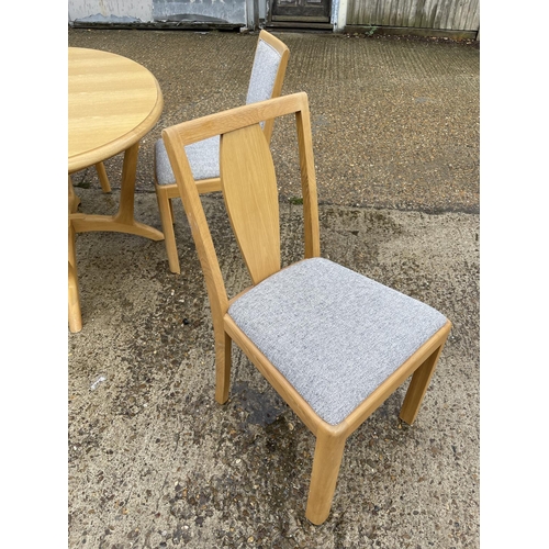 254 - A modern light oak oval dining  table together with four chairs